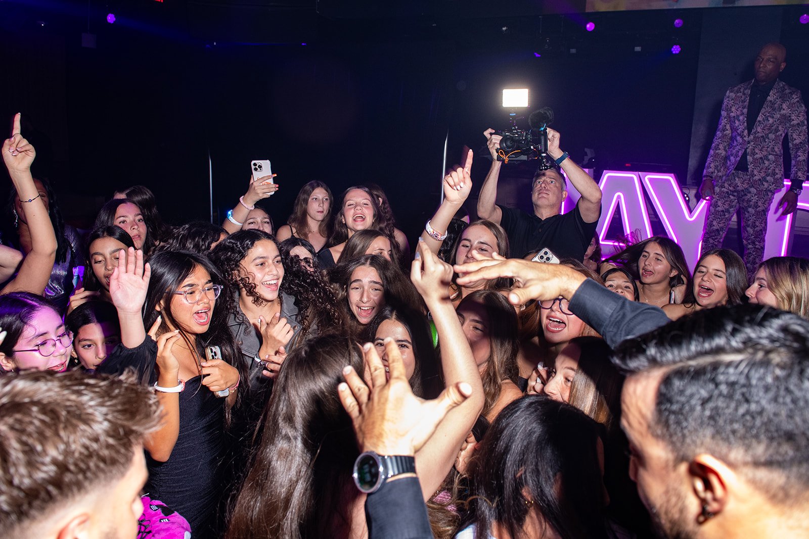 Guests dancing on a packed event dance floor while a Spotlight Media videographer films the crowd