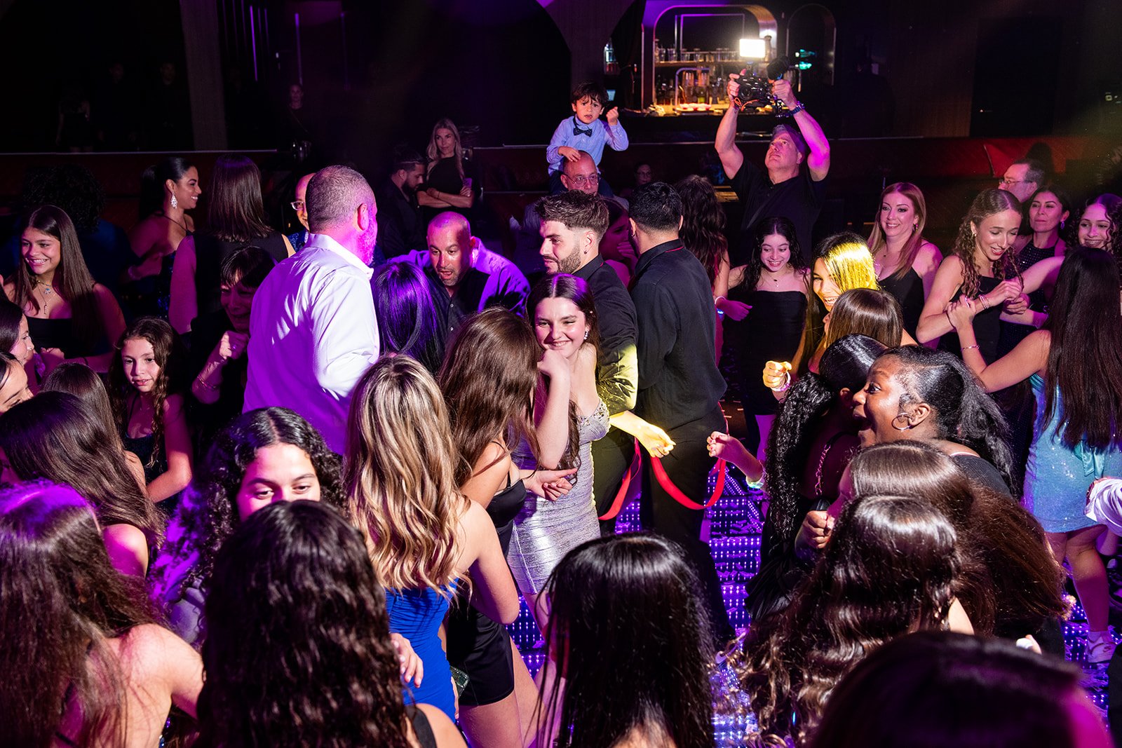 Spotlight Media crew filming guests on a lit dance floor at an evening celebration