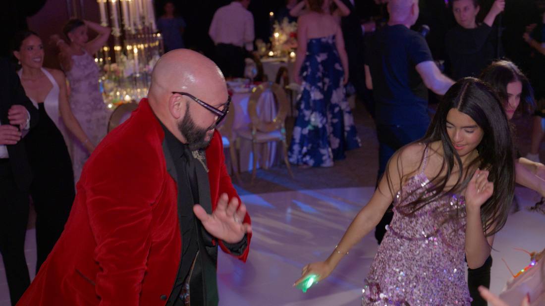 Guests dancing on the reception floor, one in a red velvet blazer