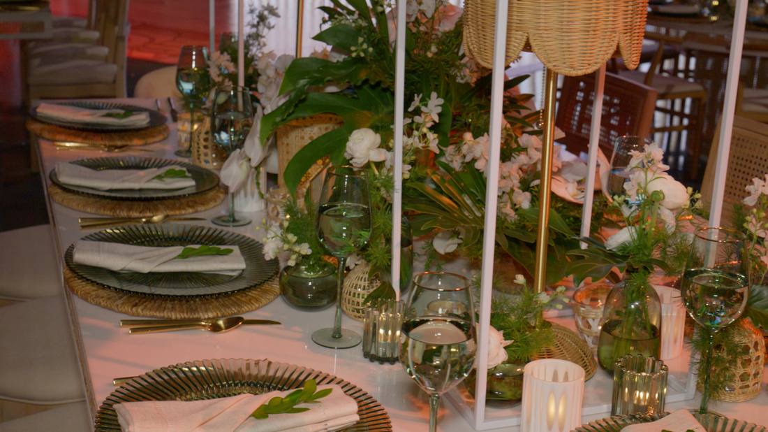 Rustic-glam table setting with greenery, wine glasses, and woven chargers