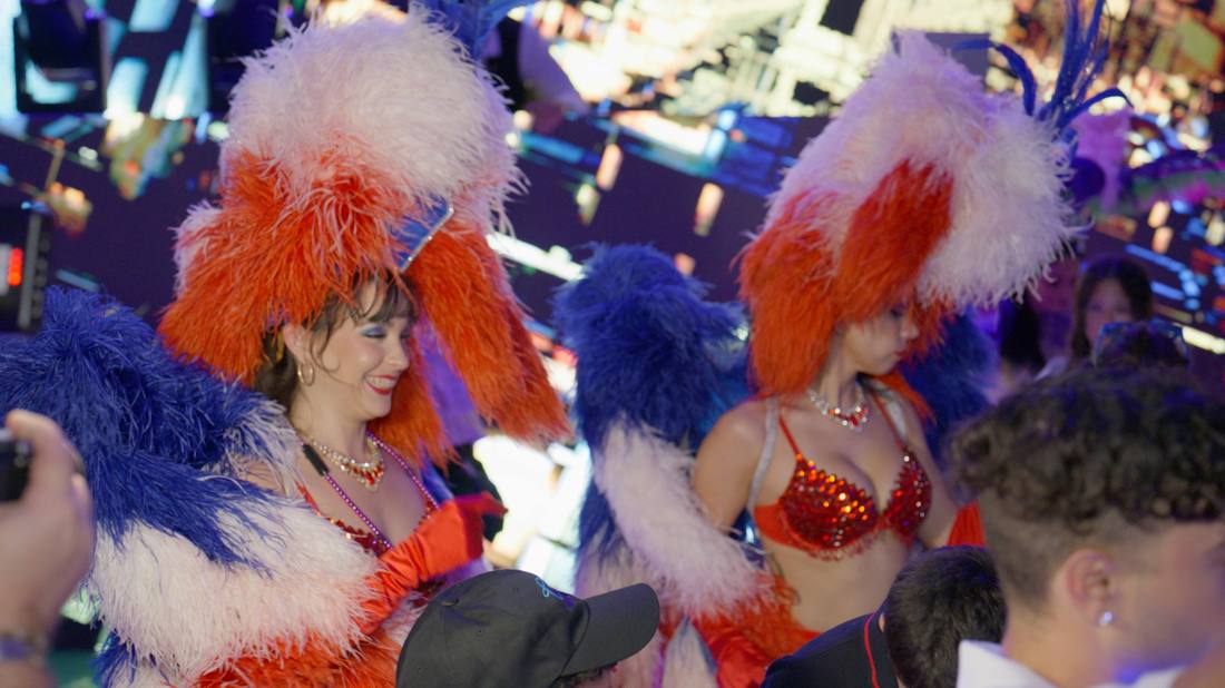 Showgirls in colorful feathered headdresses at an evening celebration