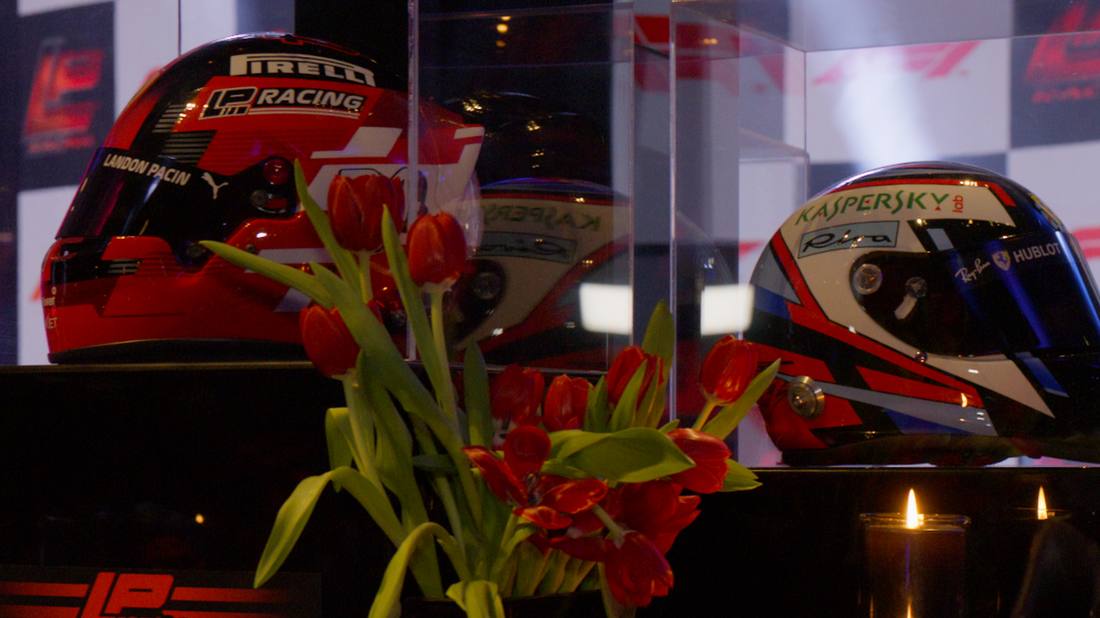 Racing helmets on display alongside red tulips in a motorsport-themed setup