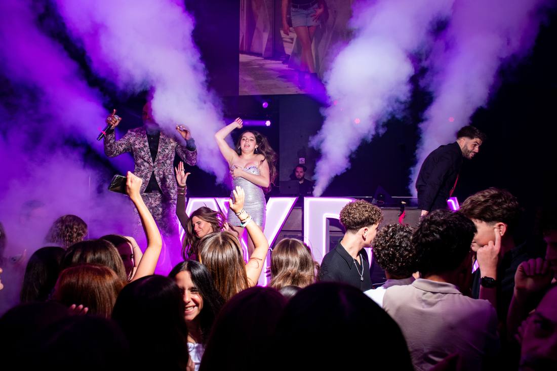 Performer and guest dancing together on stage in swirling purple haze