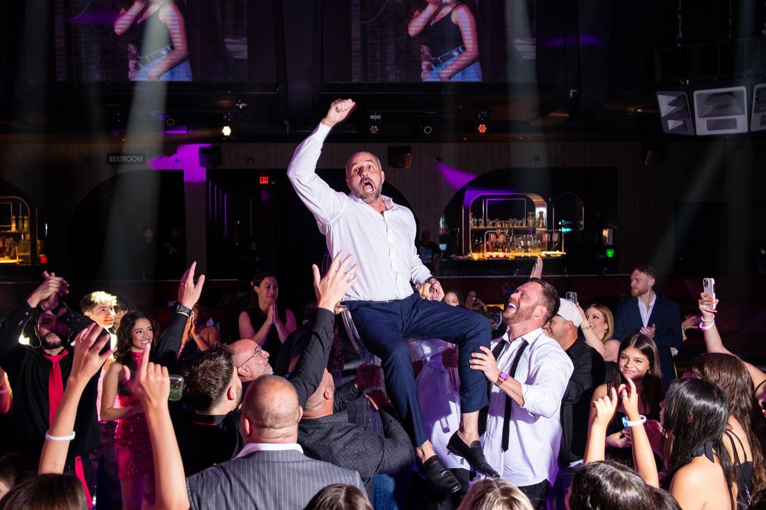 Guest lifted overhead on the dance floor near the club's bar area