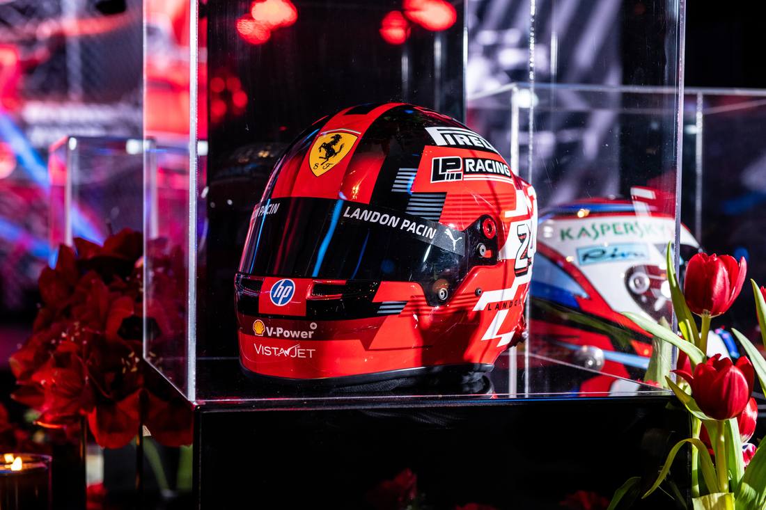 Close-up of a racing helmet on display surrounded by red tulips