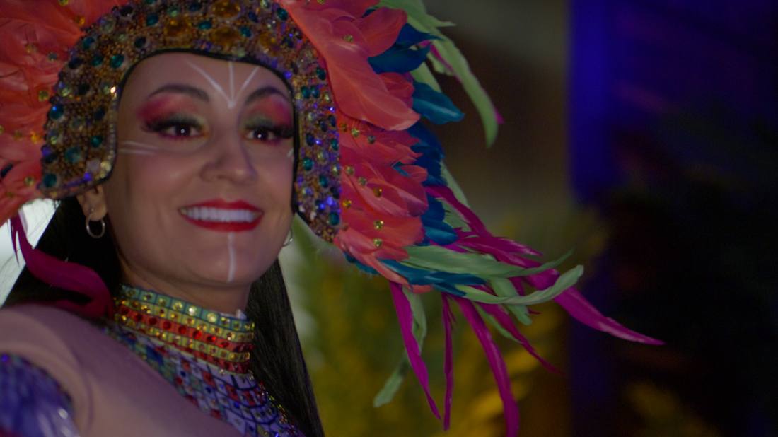 Close-up of a smiling performer in an elaborate feathered headdress