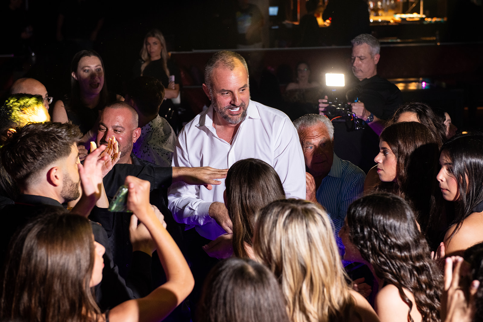 A guest of honor celebrating on the dance floor as the camera rolls
