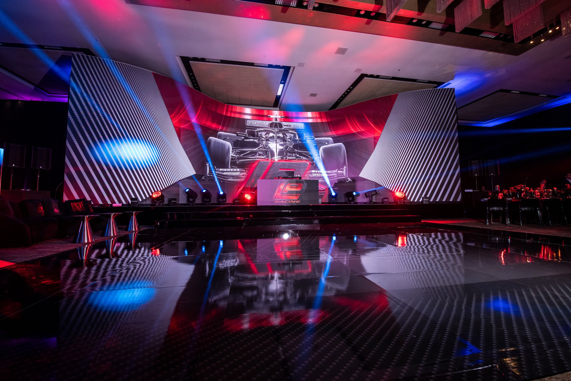 Wide view of a motorsport-themed event stage and mirrored dance floor